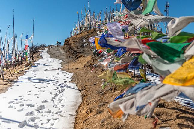 Snow on the trail with prayer flags bhutan 600x400